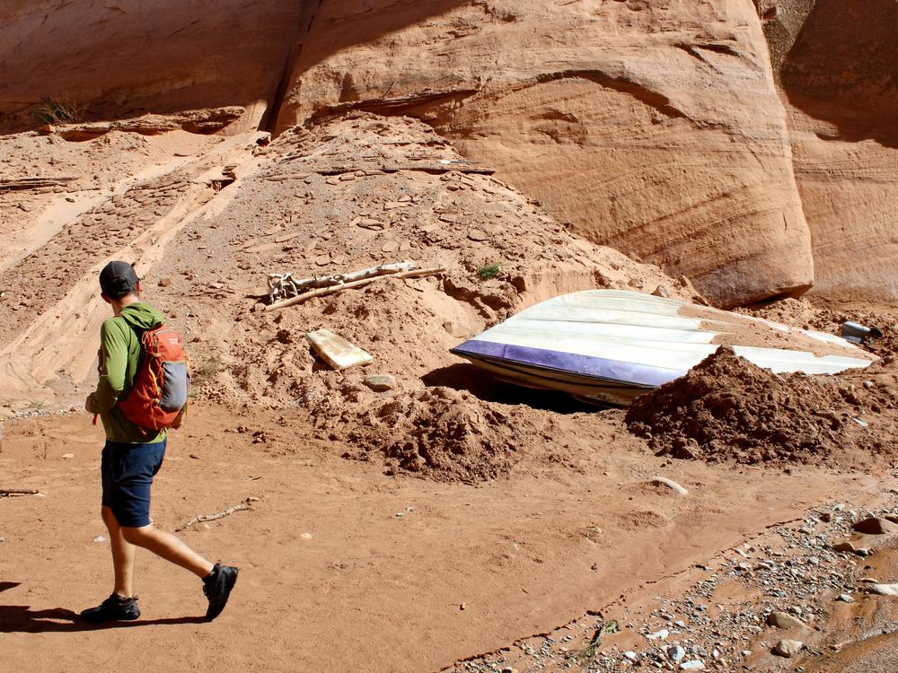 Eric Balken, with the Glen Canyon Institute, walks past a sunken speedboat in a side canyon in Glen Canyon National Recreation Area. Water levels in Lake Powell have steadily dropped, revealing areas that have been underwater for decades.