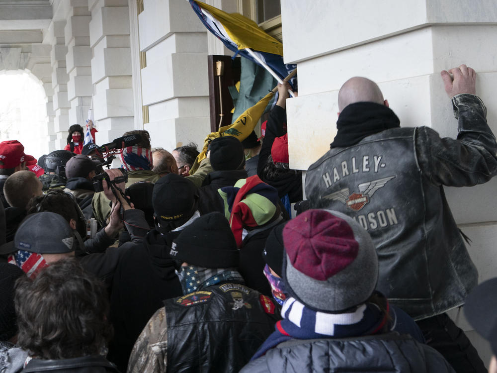Rioters try to open a door of the U.S. Capitol on Jan. 6, 2021. Three active-duty Marines have been charged in the attack.