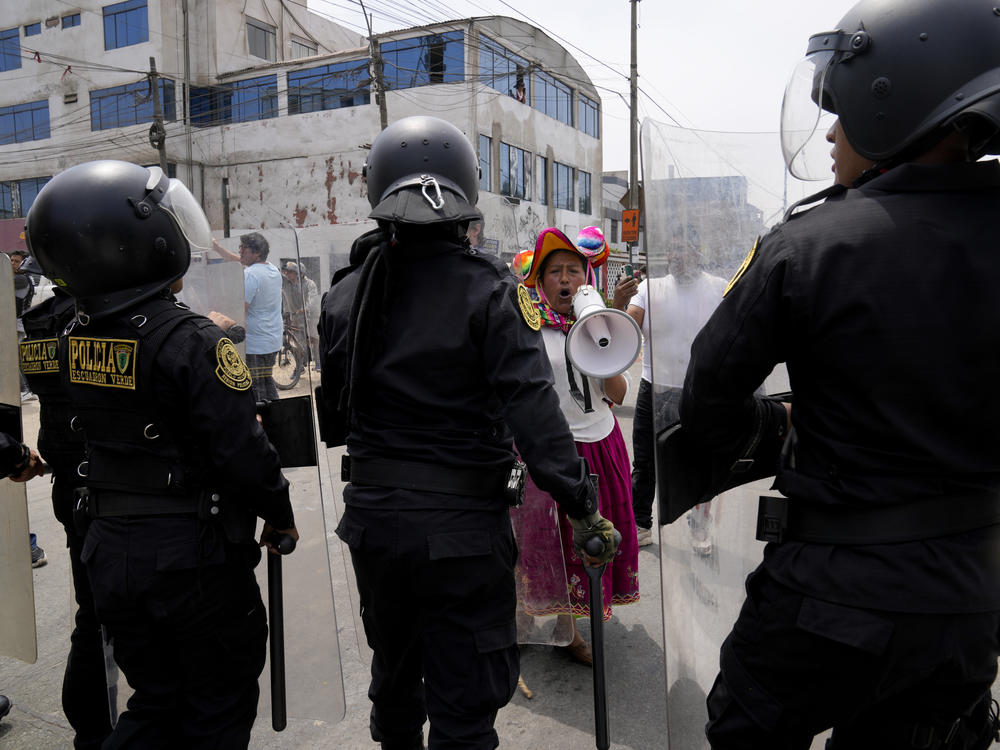 An anti-government protester challenges police surrounding the San Marcos University in Lima, Peru, Saturday, Jan. 21, 2023. Police evicted from the university grounds protesters who arrived from Andean regions seeking the resignation of President Dina Boluarte, the release from prison of ousted President Pedro Castillo and immediate elections.