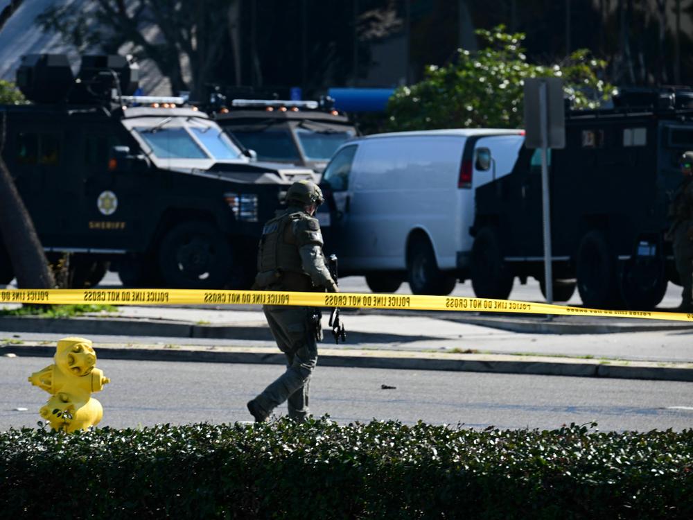 Law enforcement personnel surround a white van where the shooting suspect was found dead.