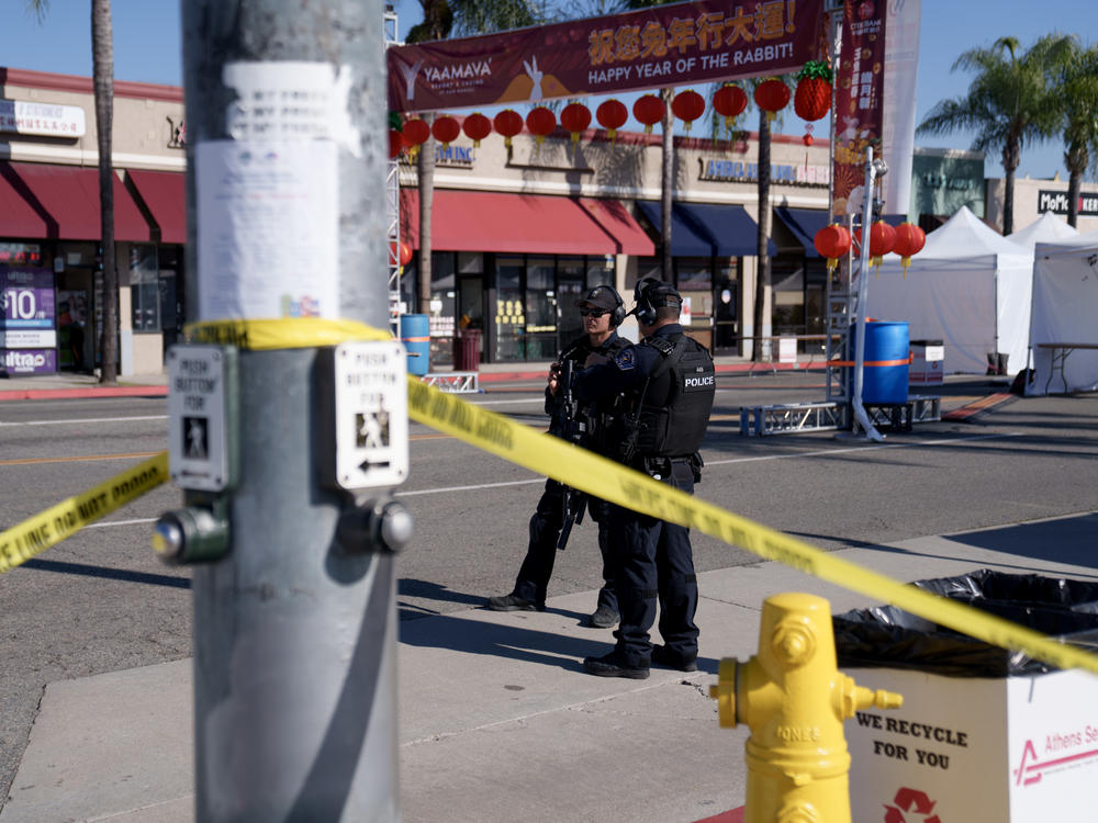 Police officers stand guard near the scene of a deadly shooting on Sunday in Monterey Park, Calif. 11 people were killed at a dance studio near a Lunar New Year celebration on Saturday night.