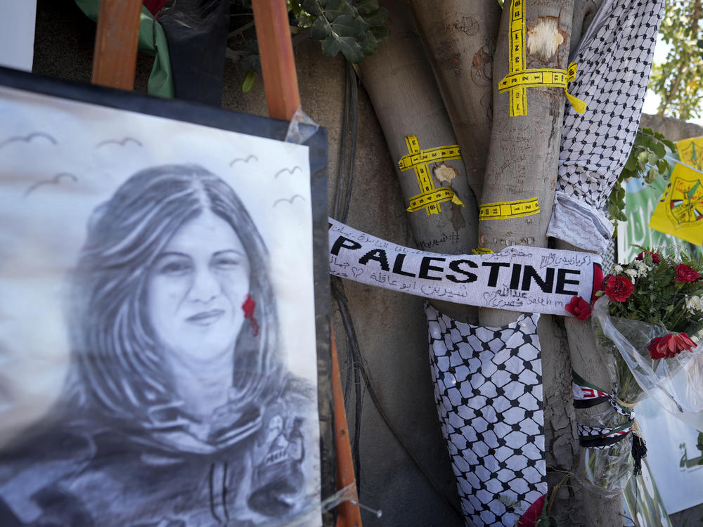 Yellow tape marks bullet holes on a tree and a portrait and flowers create a makeshift memorial, at the site where Palestinian-American Al-Jazeera journalist Shireen Abu Akleh was shot and killed in the West Bank city of Jenin, May 19, 2022.