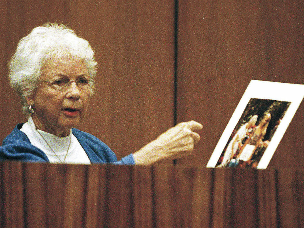Louise Ireland gestures towards a color enlargement, the last taken of her daughter, Dana Ireland, before her death, while testifying in Hilo, Hawaii, on July 26, 1999.