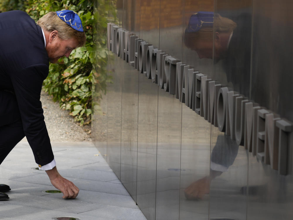 King Willem-Alexander puts a stone in an act of remembrance when unveiling a new monument in the heart of Amsterdam's historic Jewish Quarter on Sept. 19, 2021, honoring the 102,000 Dutch victims of the Holocaust.
