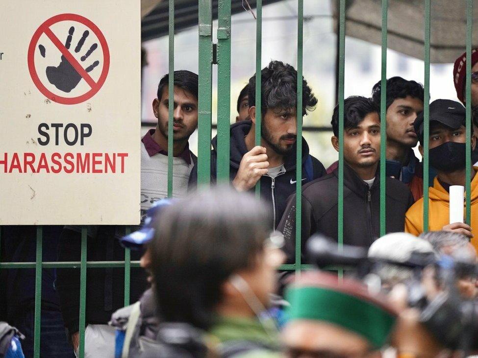 Students watch security personnel guard the main gate of Jamia Millia Islamia university Wednesday in New Delhi, India. A student group said it planned to screen a banned documentary that examines Indian Prime Minister Narendra Modi's role during 2002 anti-Muslim riots, prompting dozens of police equipped with tear gas and riot gear to gather outside campus gates.