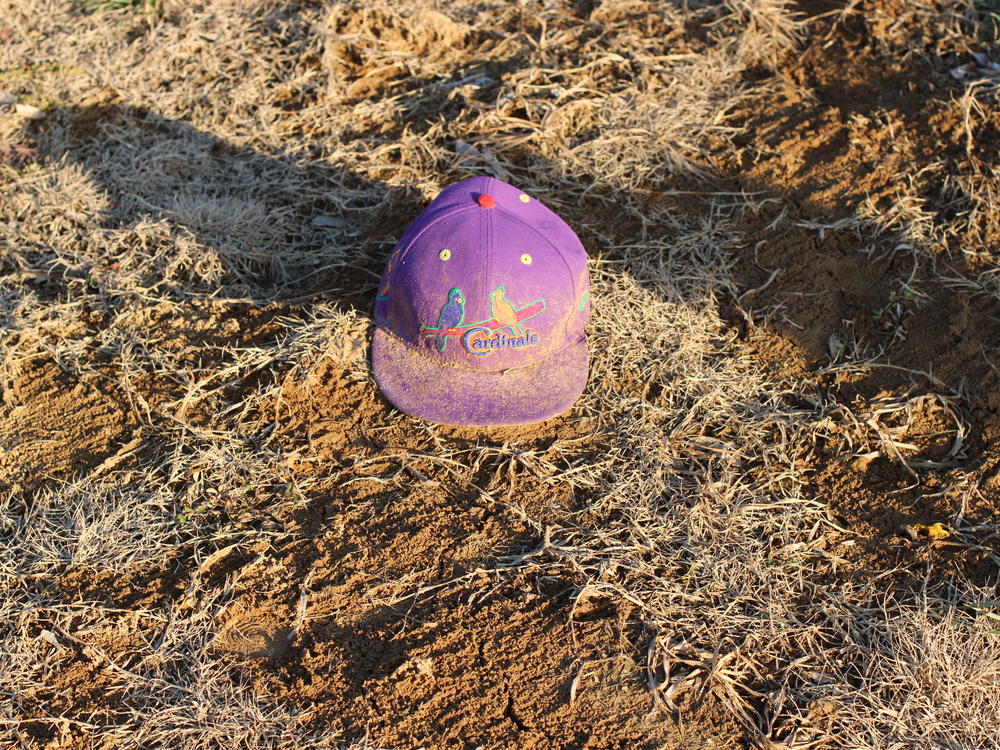 A St. Louis Cardinals baseball cap sits near a grave at Sunset Gardens of Memory in Millstadt, Illinois. In this 30-acre cemetery, groundskeepers often see memorabilia, toys, and other keepsakes near gravesites.