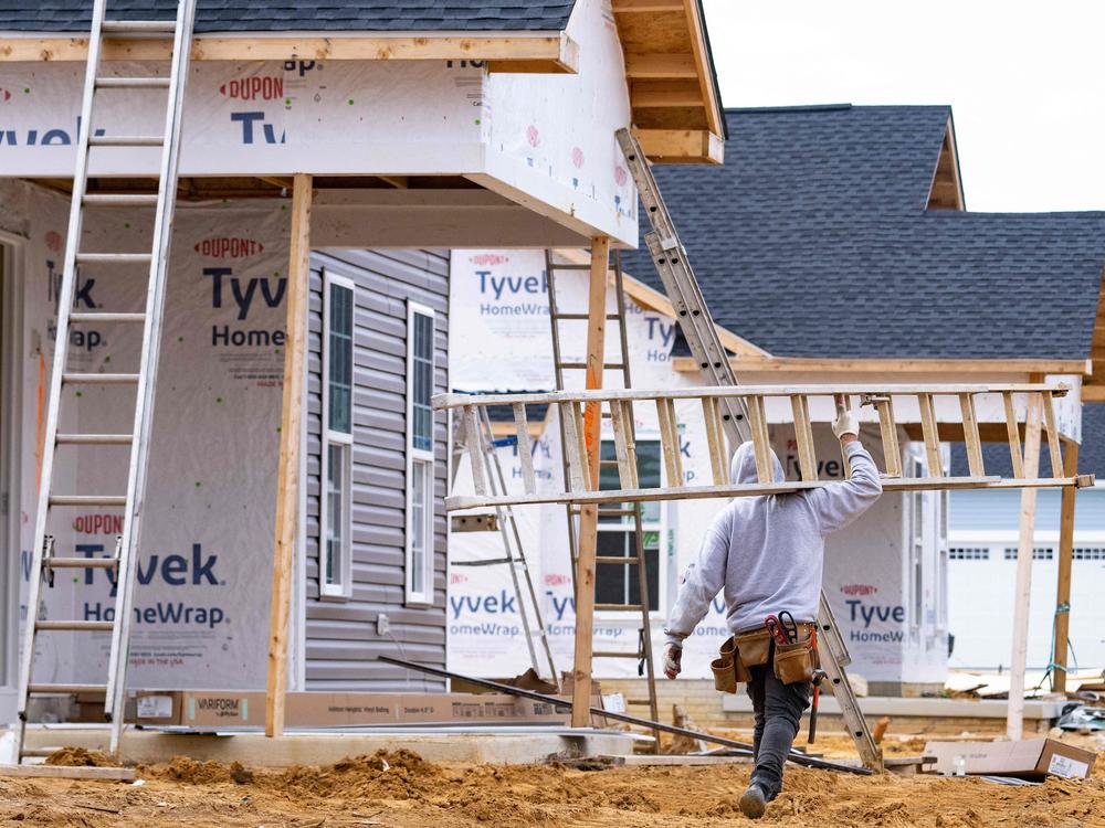 A man carries a ladder through new home construction in Trappe, Md., on Oct. 28, 2022. Mortgage rates have risen, hitting the housing sector.
