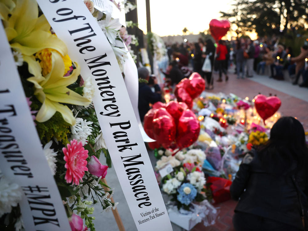 People gather at a memorial for the victims of a mass shooting over the weekend at a ballroom dance studio in Monterey Park, Calif.