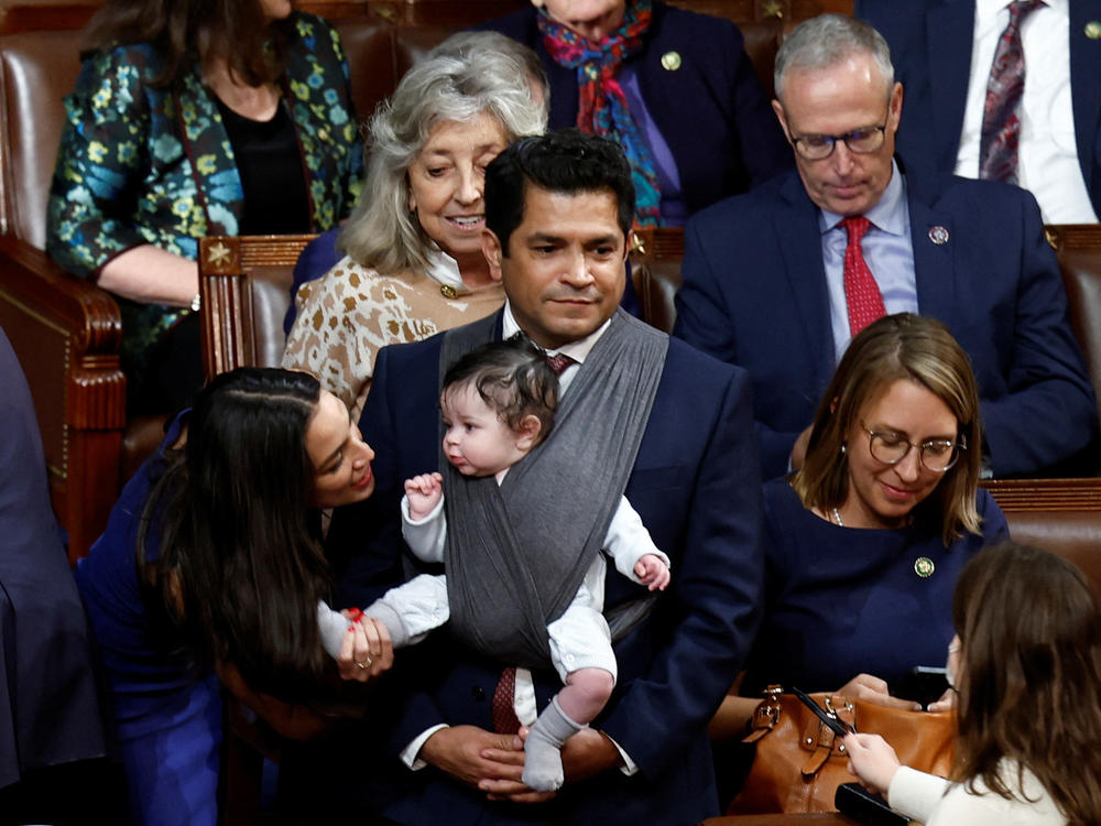 U.S. Rep. Alexandria Ocasio-Cortez, D-N.Y., talks to the infant child of Rep. Jimmy Gomez, D-Calif., inside the House chamber during votes for the next speaker of the House on the first day of the 118th Congress at the U.S. Capitol in Washington, D.C., on Jan. 3.