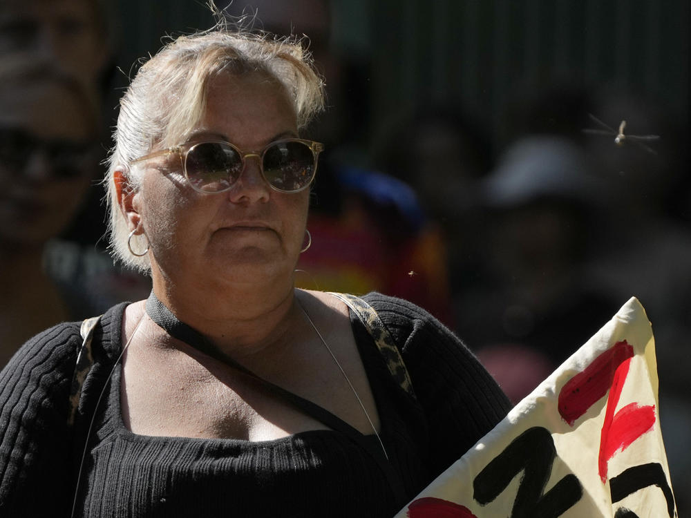A dragonfly buzzes past a woman attending an Invasion Day rally in Sydney, Thursday, Jan. 26, 2023.