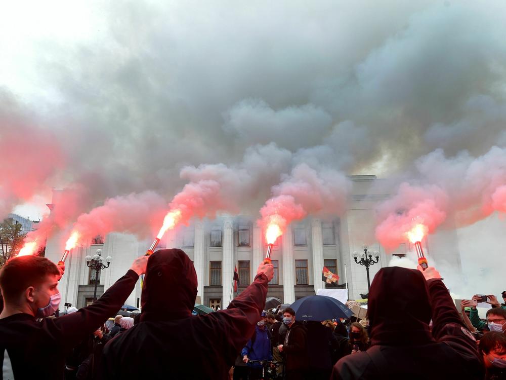 Demonstrators burn flares and smoke bombs outside the Ukrainian parliament in Kyiv on June 5, 2020, during a demonstration calling for the interior minister's resignation over corruption suspicion.