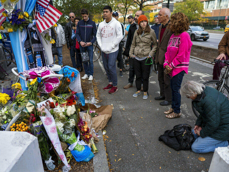 A group pauses in 2017, with some in prayer, at a makeshift memorial on a New York City bike path that that honors victims of an attack who were stuck and killed by a rental truck driven by Sayfullo Saipov. The Islamic extremist was convicted of federal crimes on Thursday and could face the death penalty.