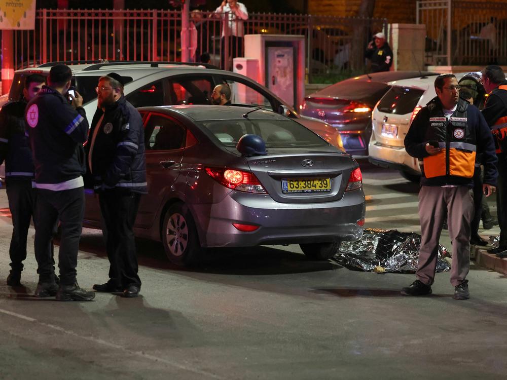 Israeli emergency service personnel and security forces stand near a covered body at the site of a reported attack in Jerusalem on Friday.