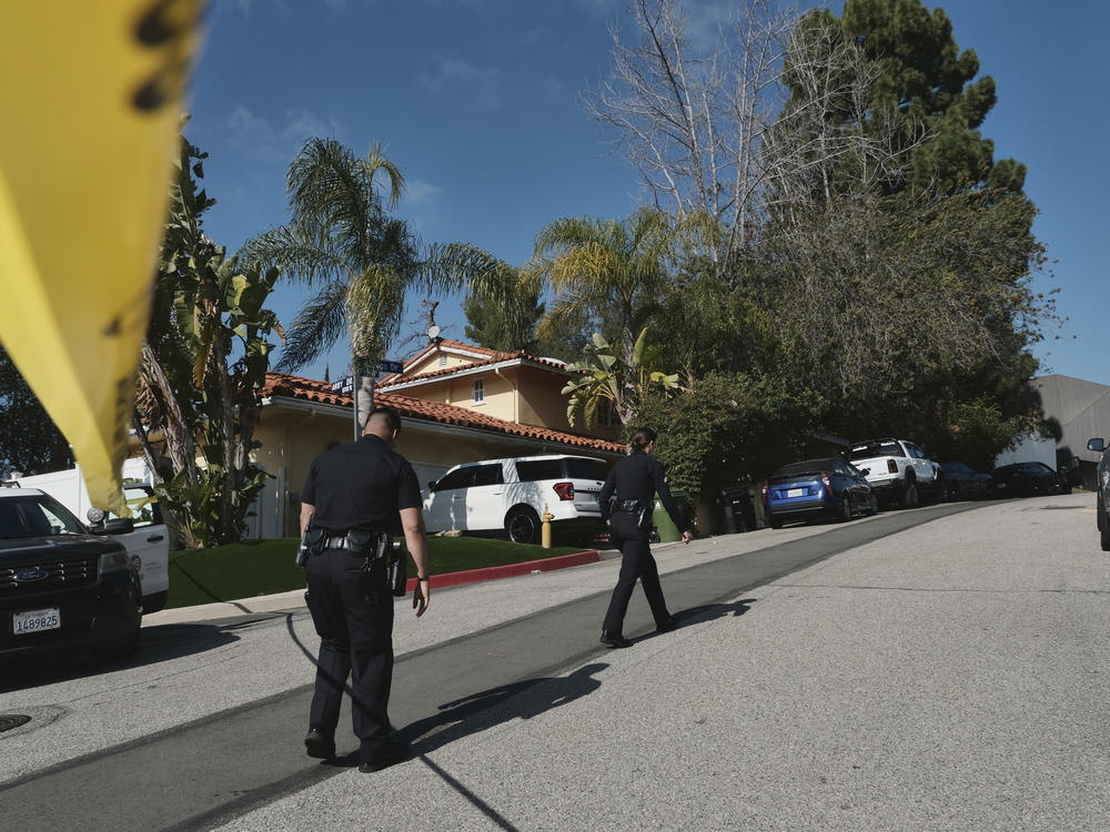 Police block the street to a house where three people were killed and four others wounded in a shooting at a short-term rental home in an upscale Los Angeles neighborhood on Saturday.