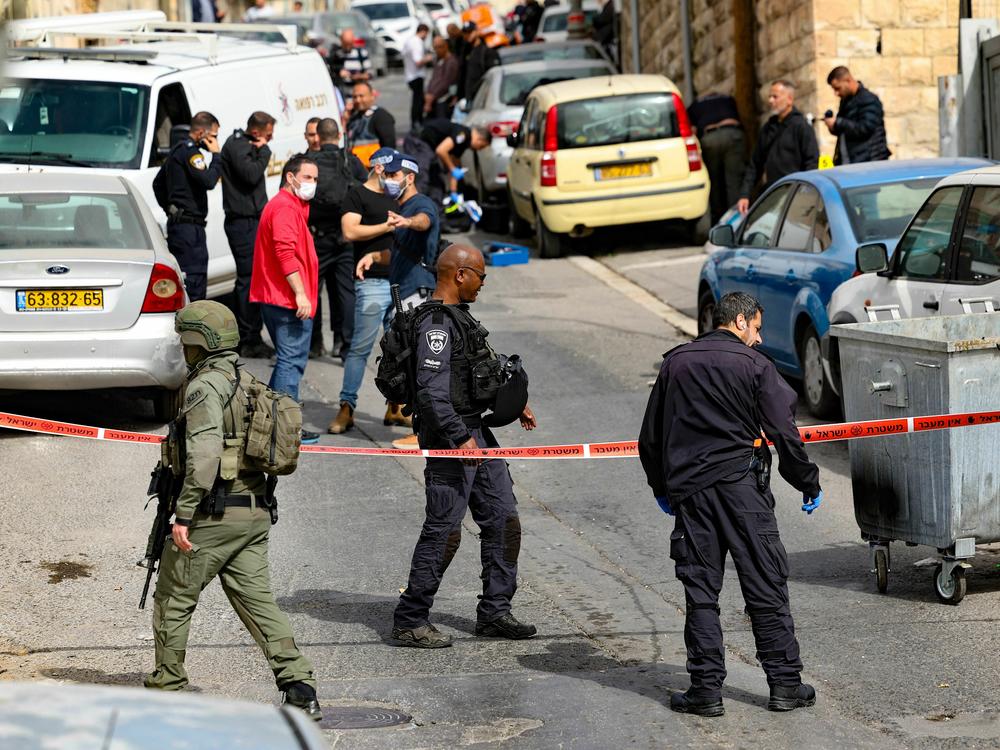 Israeli security forces and emergency service personnel gather at a cordoned-off area in Jerusalem's predominantly Arab neighborhood of Silwan, where police say an assailant shot and wounded two people on Saturday.