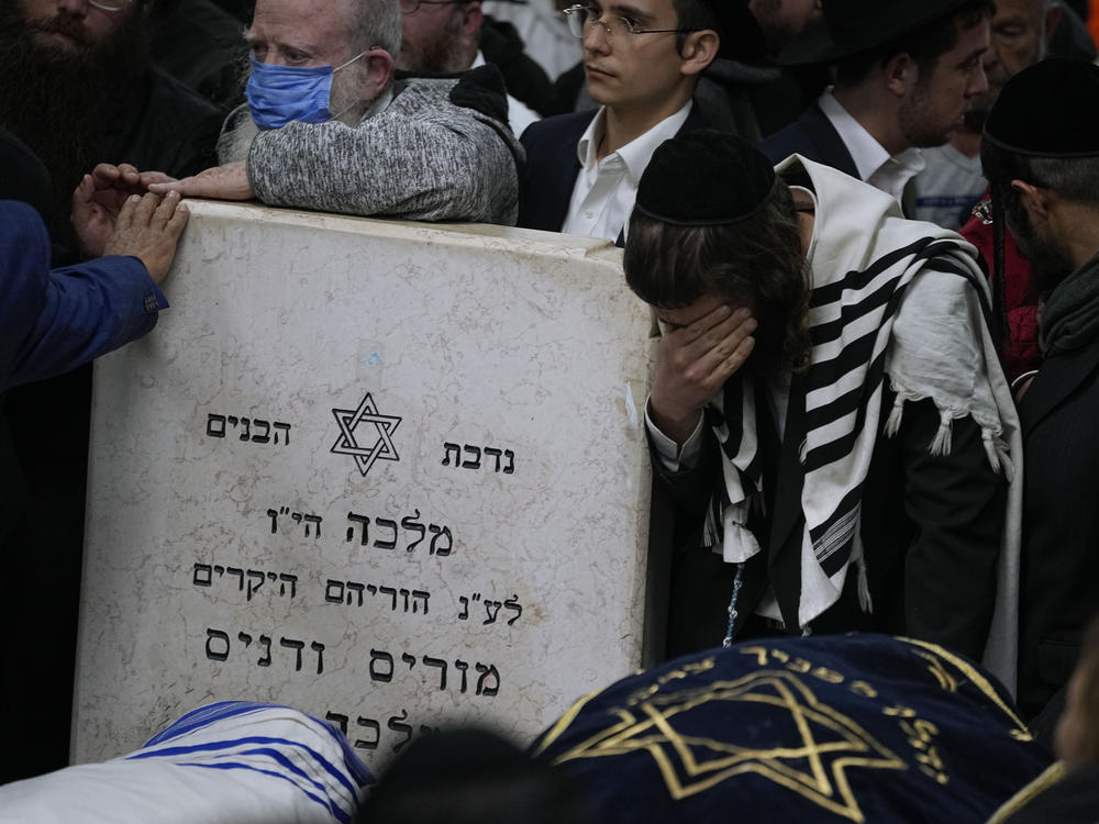 Mourners gather around the bodies of Israeli couple Eli Mizrahi and his wife, Natalie, victims of a shooting attack Friday in east Jerusalem, during their funeral at the cemetery in Beit Shemesh, Israel, early Sunday, Jan. 29, 2023.