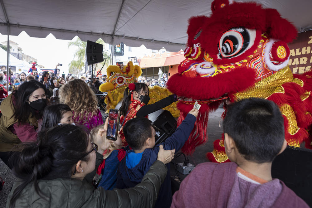 Children feed red envelopes and money to a red dragon during this year's Alhambra Lunar New Year Festival in Alhambra, Calif.