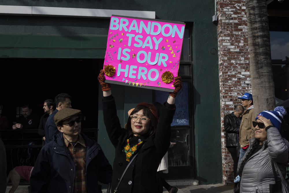 Becki Peng of Alhambra holds a sign honoring Brandon Tsay as she waits in line to meet him at the Alhambra Lunar New Year Festival.