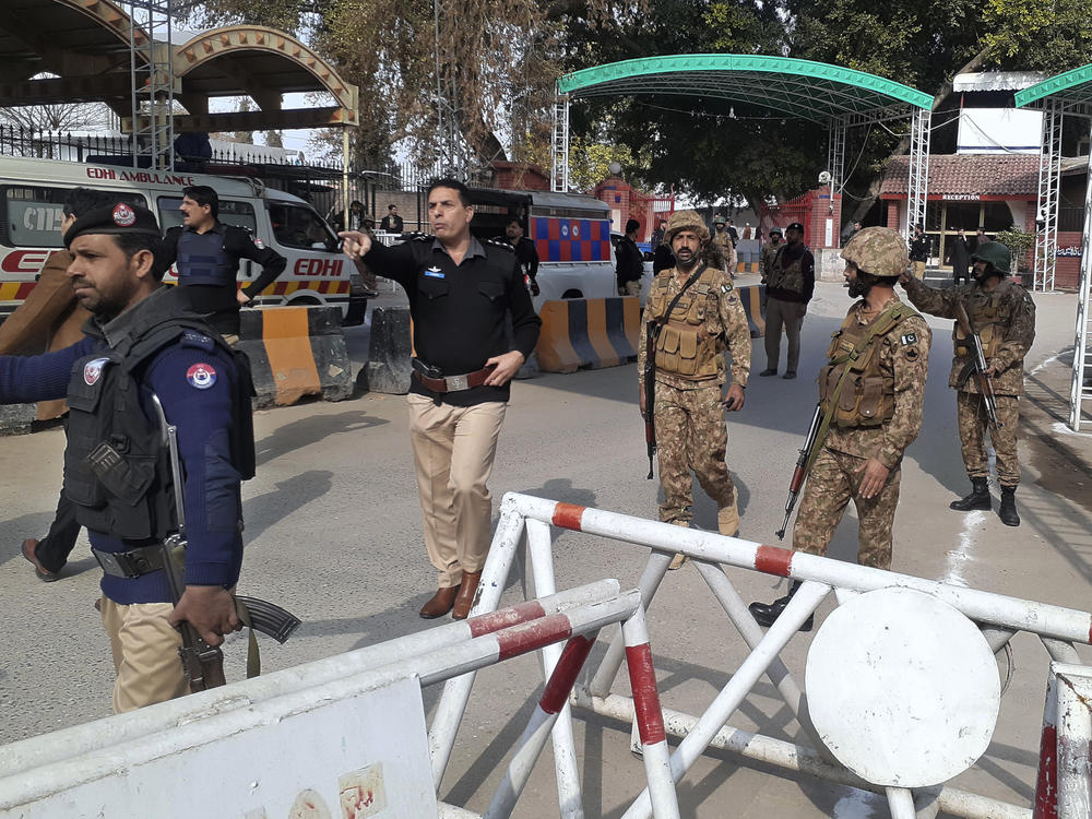 Army soldiers and police officers clear the way for ambulances rushing toward a bomb explosion site, at the main entry gate of police offices, in Peshawar, Pakistan, Monday, Jan. 30, 2023.