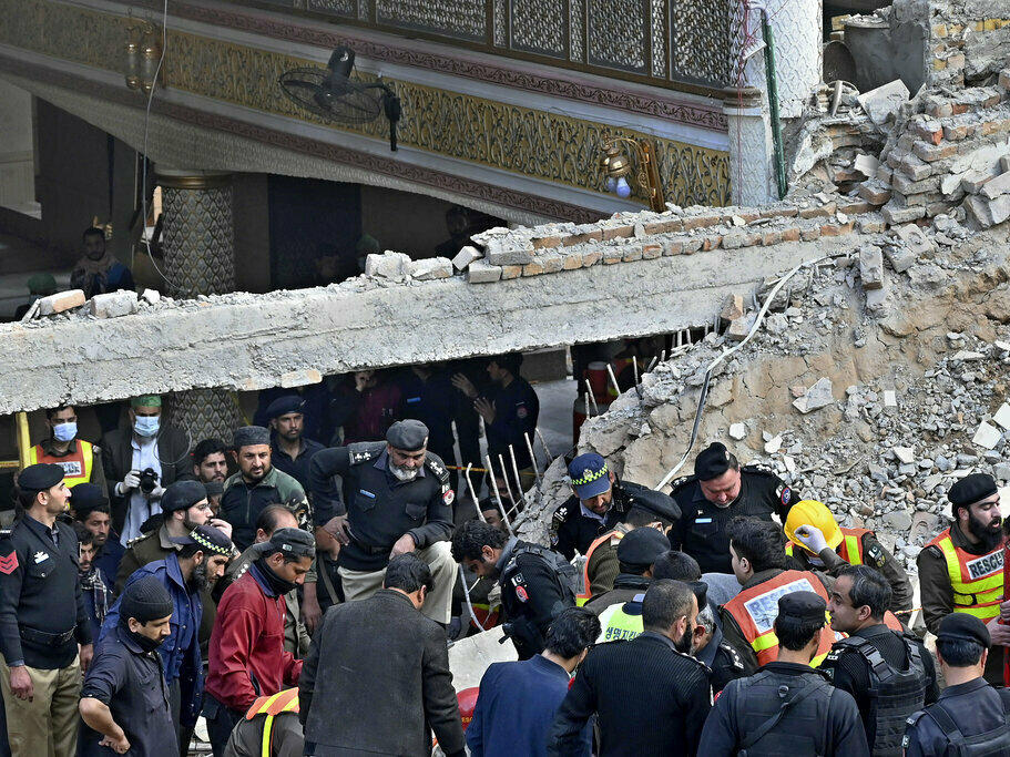 Security officials and rescue workers search for bodies Monday at the site of suicide bombing, in Peshawar, Pakistan.