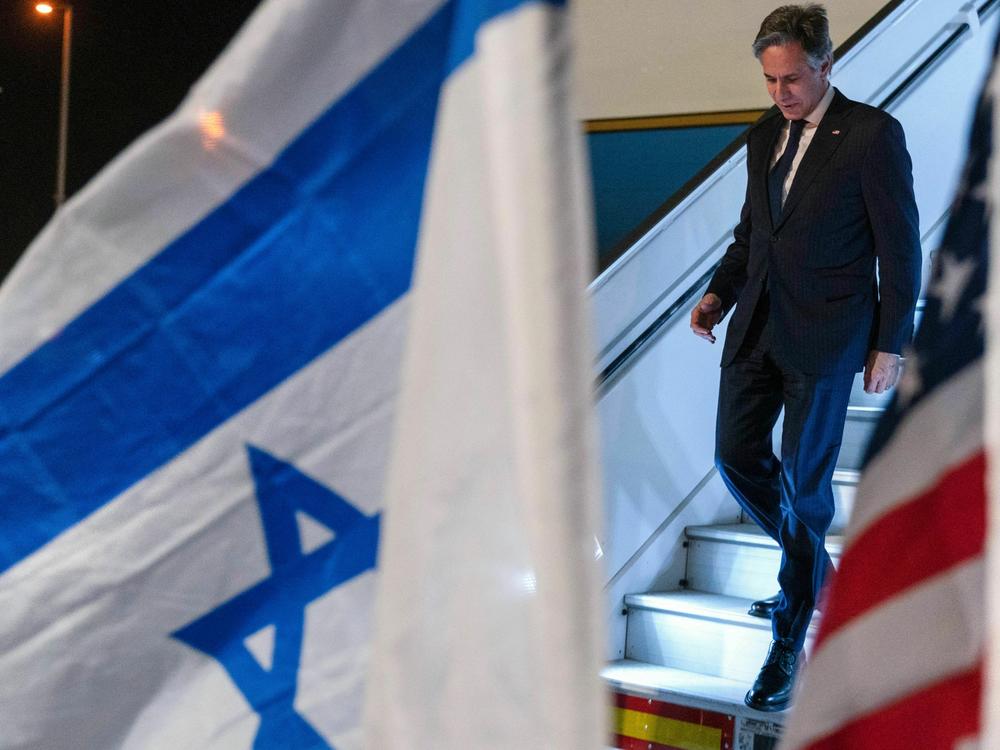 U.S. Secretary of State Antony Blinken walks by U.S. and Israeli flags upon arrival to Ben Gurion airport near Tel Aviv.