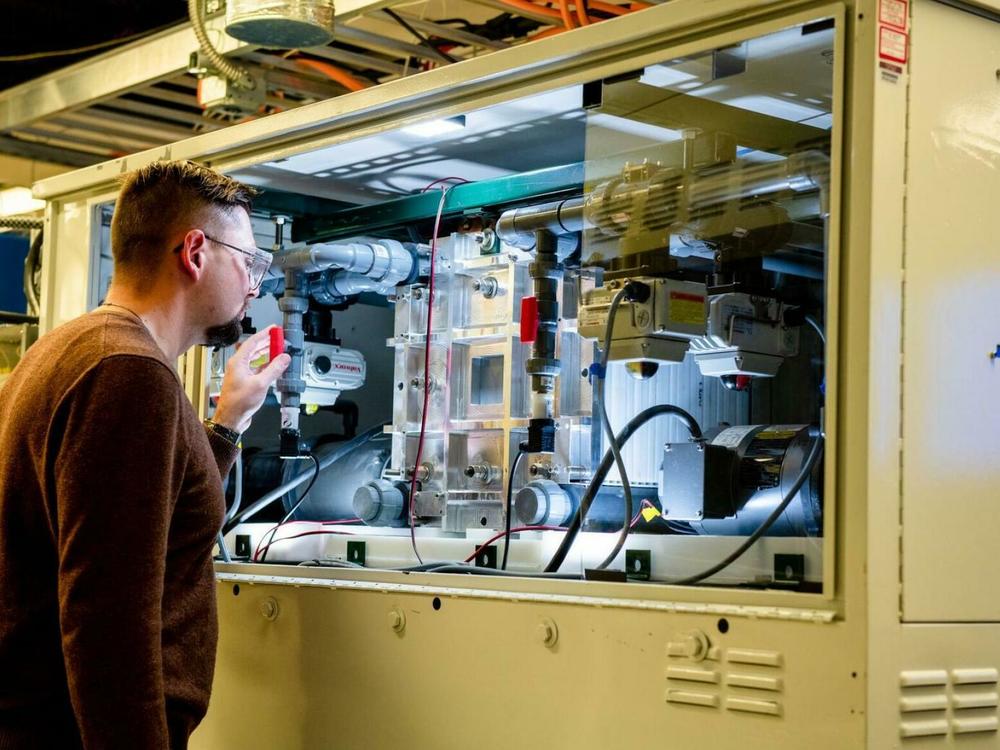 An employee examines a vanadium flow battery stack in the Battery Reliability Test Laboratory at PNNL.
