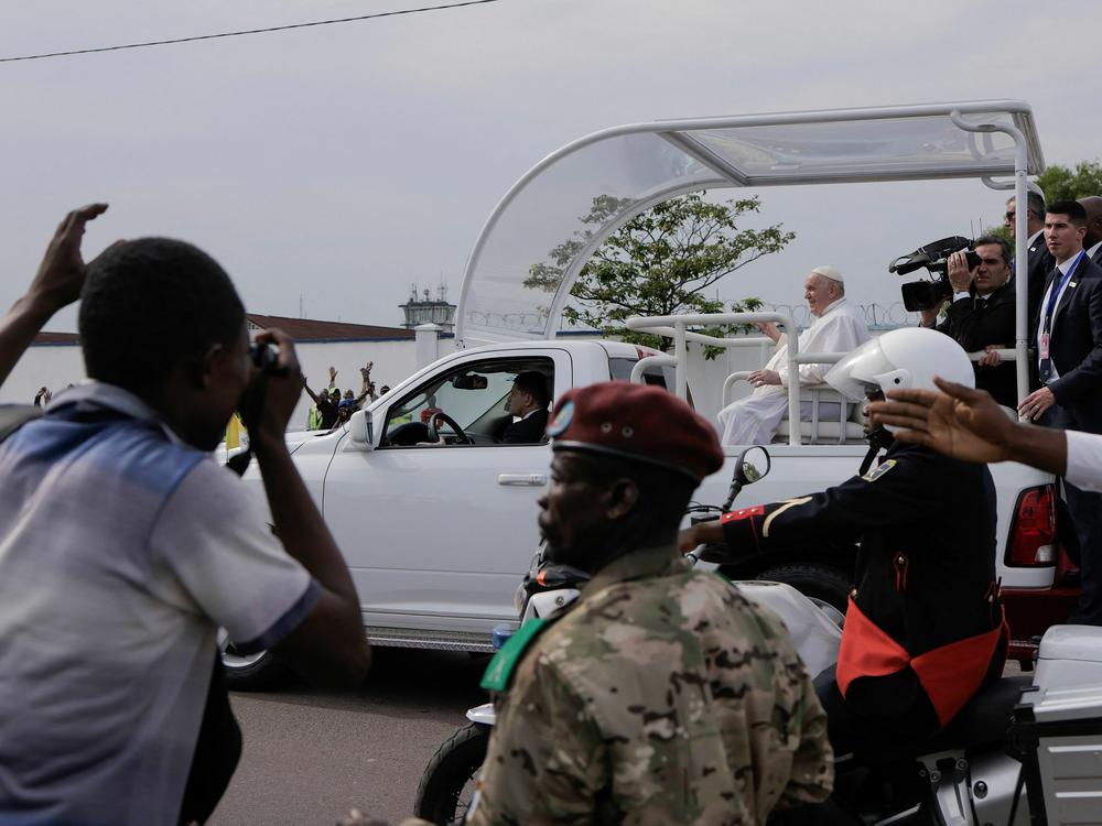 Bystanders look on as Pope Francis travels by popemobile as he departs the airport in the Democratic Republic of Congo.