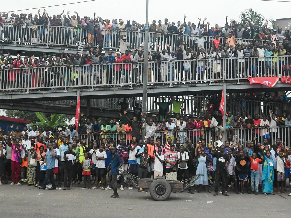 People gathering on the side of the road wave as Pope Francis departs the N'djili International Airport in Kinshasa.