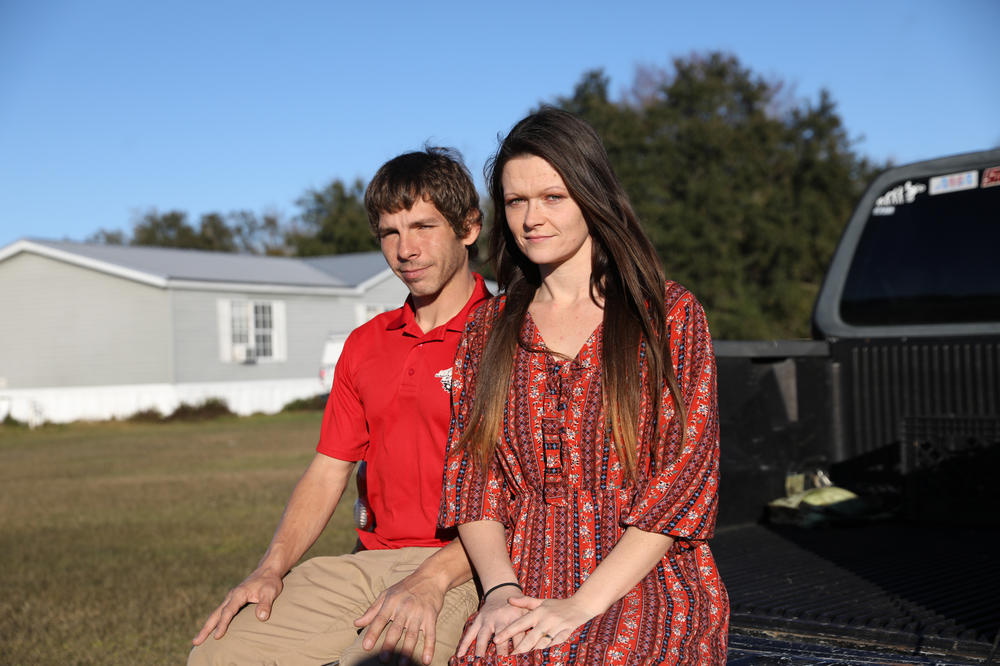 Darren and Courtney Johnson sit on the back of a truck outside their home in Center Hill, Fla. Three weeks after they bought a used SUV and took it home, they were told by a dealership manager that they needed to return and sign a new contract with different terms. Things went downhill from there.