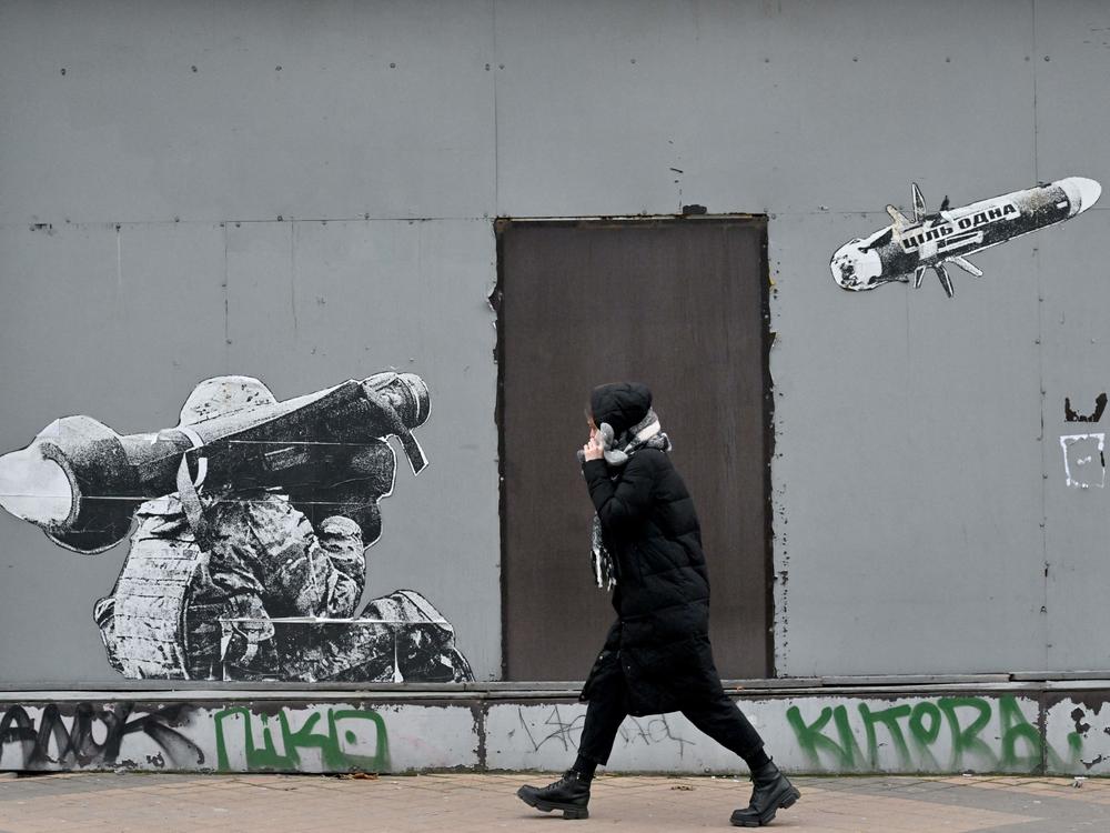 A woman walks past graffiti depicting a Ukrainian soldier firing a missile, in Kyiv on Jan. 25. The Russians are fighting an intense air war, but it involves mostly missiles, drones and anti-aircraft system. Traditional air strikes by piloted war planes have been relatively rare.