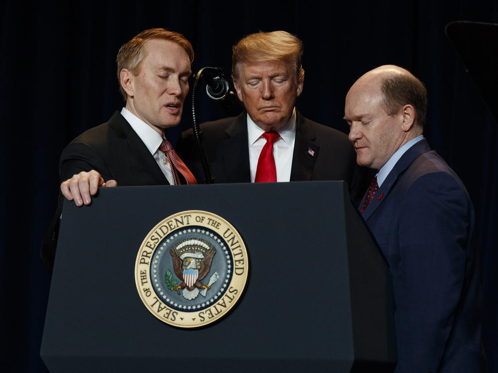 Rep. James Lankford, R-Okla., left, President Donald Trump, center, and Sen. Chris Coons, D-Del., pray during the National Prayer Breakfast in 2019.