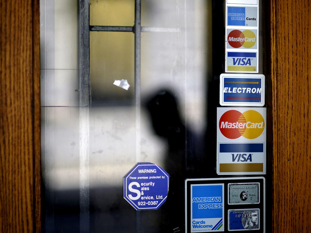 Credit card logos are seen on a downtown storefront as a pedestrian passes in Atlanta in 2012.