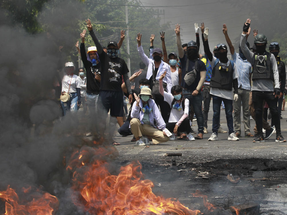 Anti-coup protesters gesture with a three-fingers salute, a symbol of resistance during a demonstration during by police crack down in Thaketa township Yangon, Myanmar, Saturday, March 27, 2021.