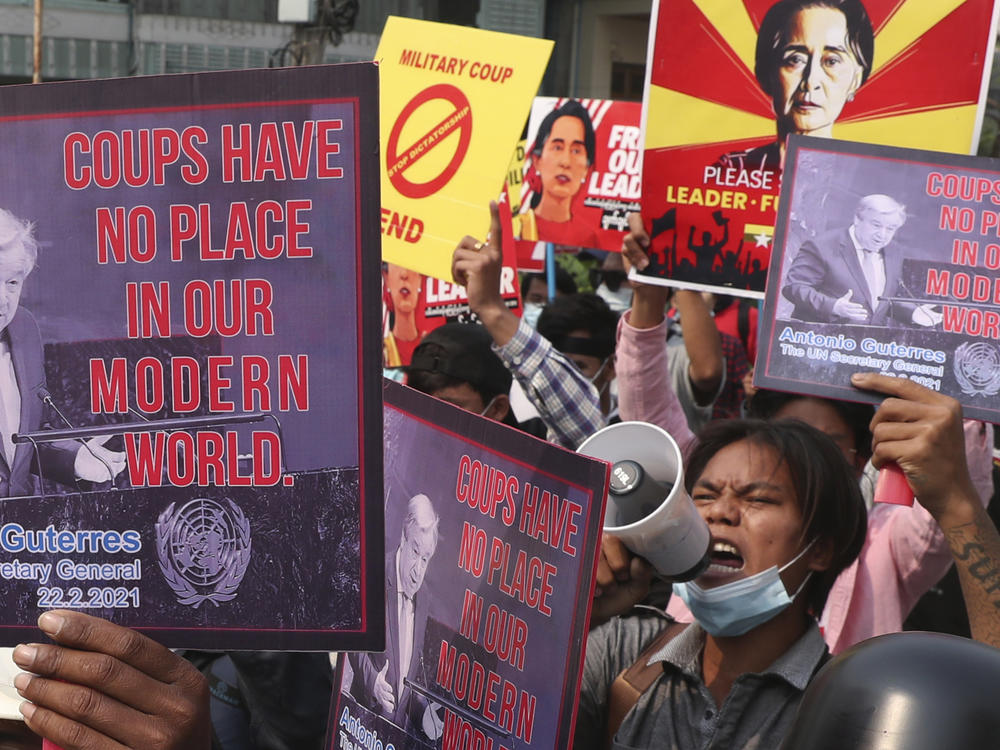 Anti-coup protesters hold up signs as they march in Mandalay, Myanmar Sunday, March 14, 2021. The prospects for peace in Myanmar, much less a return to democracy, seem dimmer than ever two years after the army seized power from the elected government of Aung San Suu Kyi, experts say.