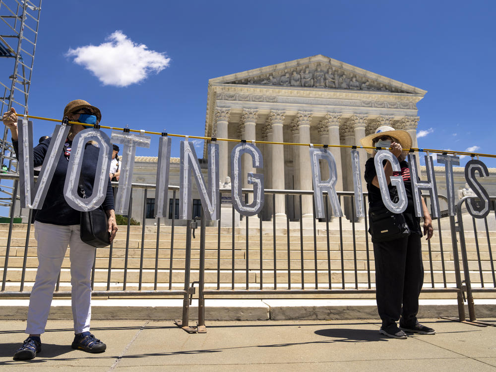 Demonstrators hold up large cut-out letters spelling 