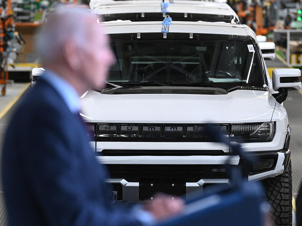 The GMC Hummer EV is seen behind President Biden as he speaks during a visit to the General Motors Factory Zero electric vehicle assembly plant in Detroit on November 17, 2021. Not all automakers are expected to cut prices for their electric cars. GM CEO Mary Barra said she doesn't plan to cut prices on the Cadillac Lyriq, for example.