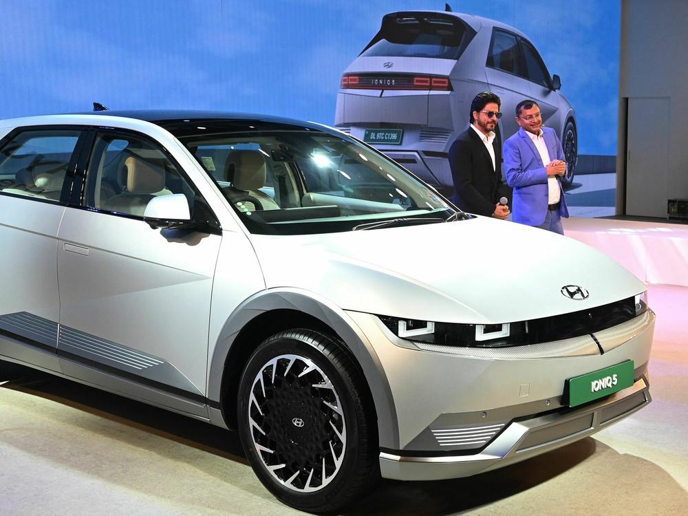 Bollywood actor Shah Rukh Khan, left, and a Hyundai executive in India pose in front of the Hyundai IONIQ 5 during the Auto Expo 2023 in Greater Noida, India, on Jan. 11, 2023. Interest in electric cars is growing around the world.
