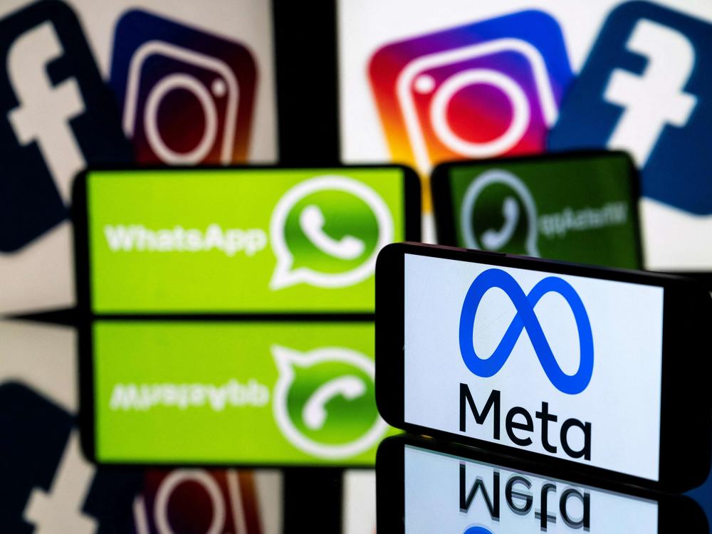 This picture taken on January 12, 2023 in Toulouse, southwestern France shows a smartphone and a computer screen displaying the logos of the Instagram, Facebook, WhatsApp and their parent company Meta.