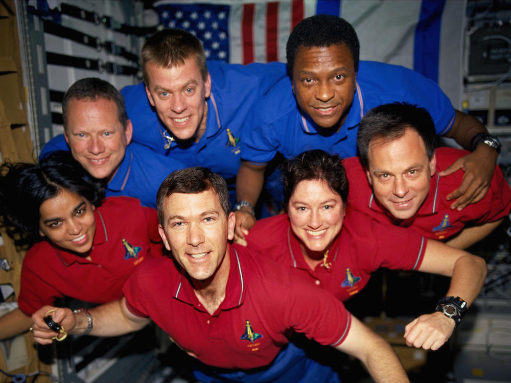 A portrait of the STS-107 crewmembers aboard the Space Shuttle Columbia in early 2003. From the left (bottom row), wearing red shirts to signify their shift's color, are Kalpana Chawla, Rick D. Husband, Laurel B. Clark, and Ilan Ramon. From the left (top row) are David M. Brown, William C. McCool and Michael P. Anderson.