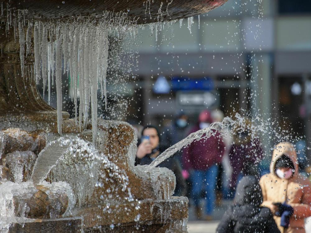 Pedestrians view a partially frozen fountain on a cold-weather day on Jan. 11 in New York City.