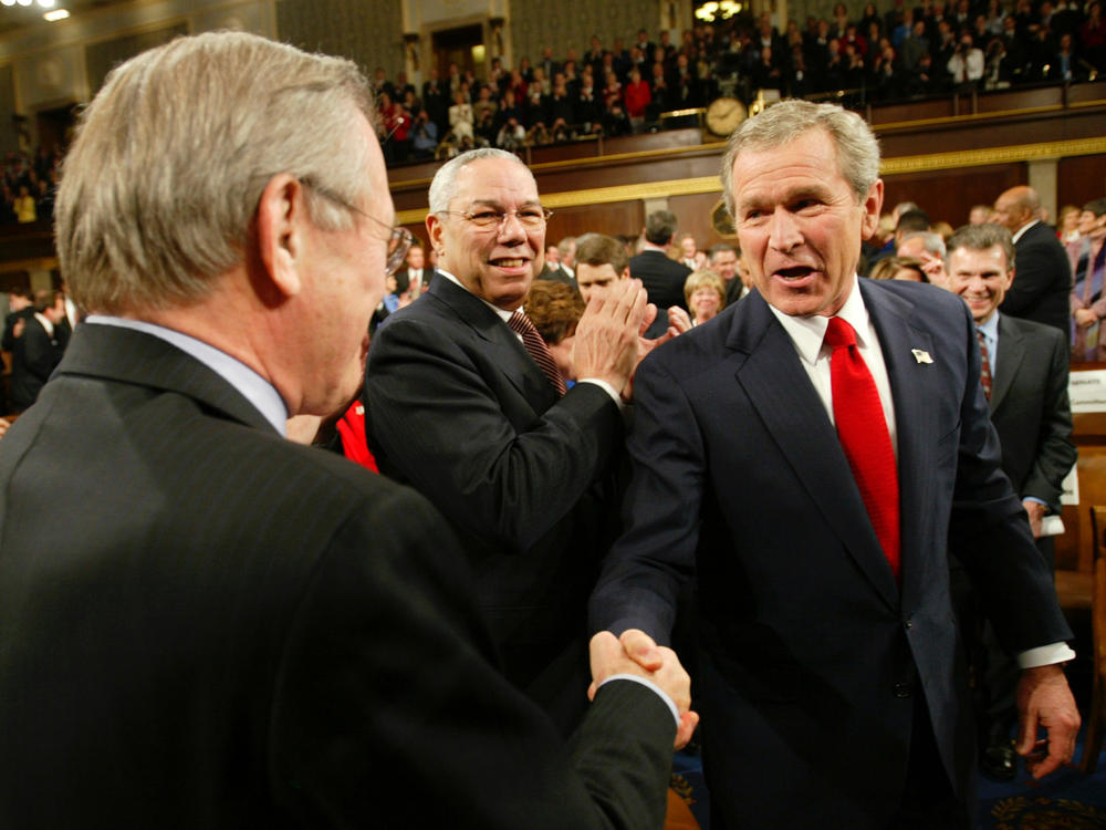 President George W. Bush shakes hands with Defense Secretary Donald Rumsfeld as Bush makes his way into the House chamber for his 2004 State of the Union address.