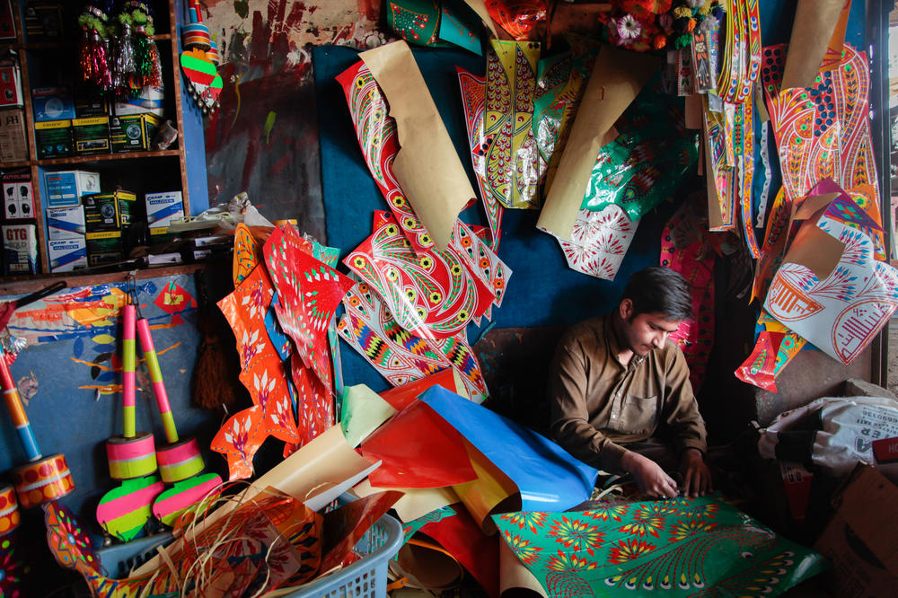 An artisan finely slices reflective stickers into intricate pieces to be assembled into designs on a Belorusian tractor. Side-by-side workshops line the main road of the market town of Mandi Bahauddin in the Pakistani province of the Punjab where tractors are transformed with exuberant designs.