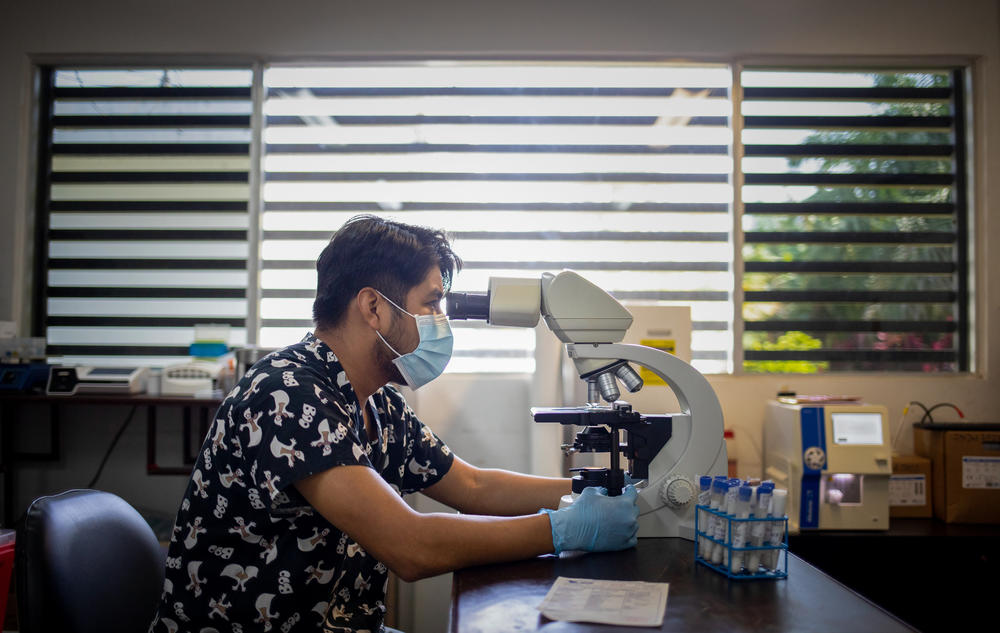 José Anaya looks at a blood sample under a microscope in one of the FunSalud laboratory buildings.
