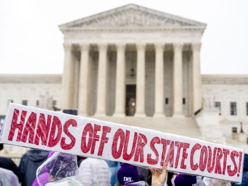 A demonstrator holds up a sign that reads 