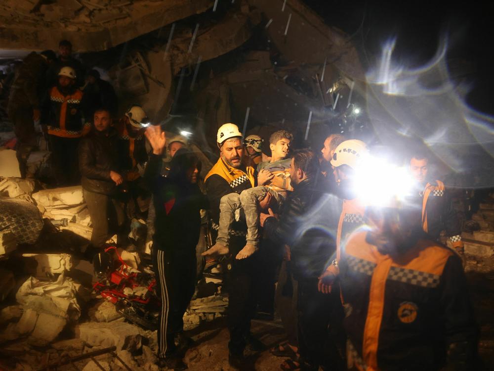 Rescue workers carry a boy they recovered from the rubbles of a building after an earthquake in Dana, a town in rebel-held Idlib, early Monday morning.