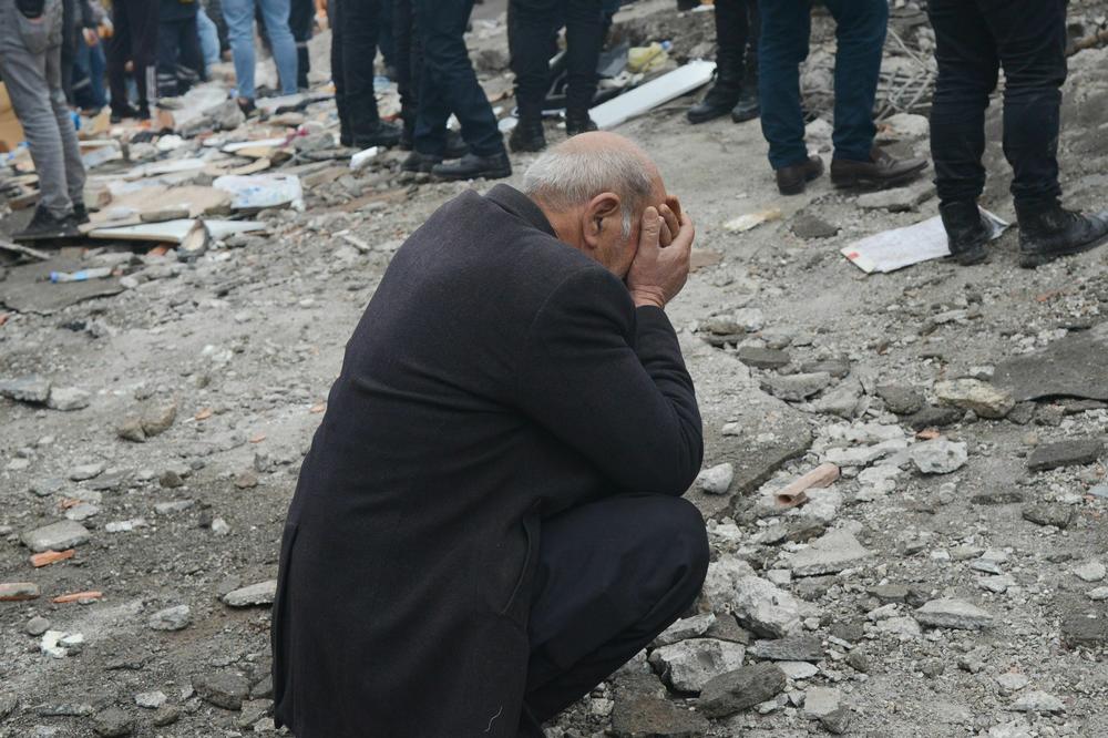 A man covers his face as people search for survivors through the rubble in Diyarbakir, Turkey, after a 7.8-magnitude earthquake struck the country's south-east.