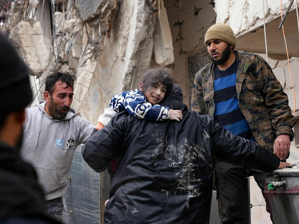 Residents retrieve a small child from the rubble of a collapsed building following an earthquake in the town of Jandaris, in the countryside of Syria's northwestern city of Afrin, on Monday.