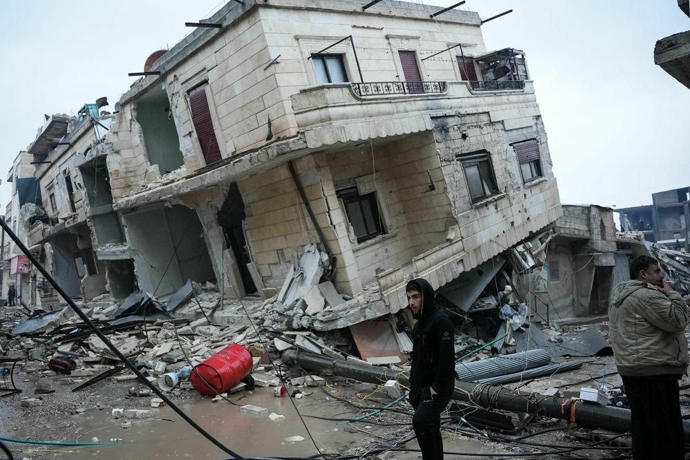 Residents stand in front of a collapsed building following an earthquake in the town of Jandaris, Syria.