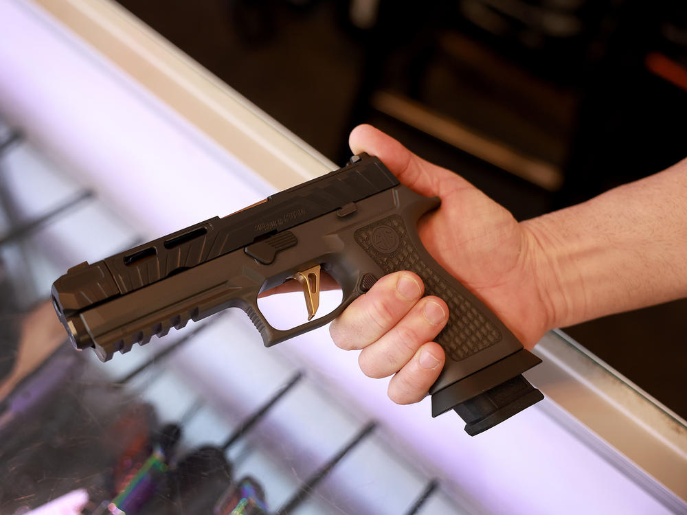 A Sig Sauer P320 handgun is held at a store.