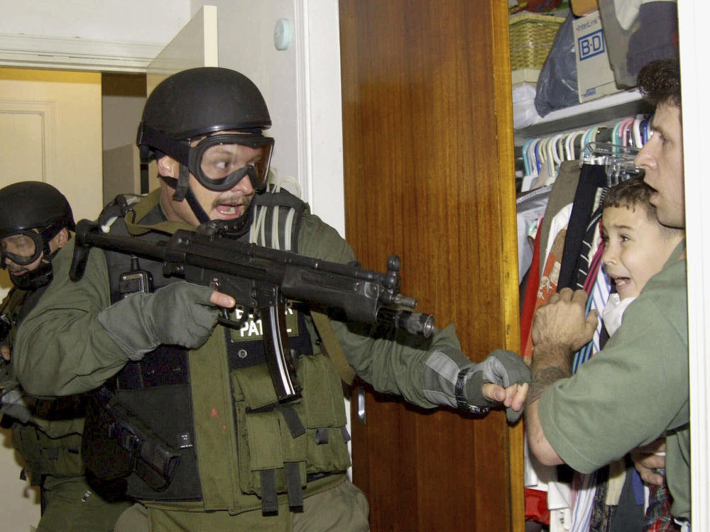 In this April 22, 2000, photo by Associated Press photojournalist Alan Diaz, Elián González is held in a closet by Donato Dalrymple, right, as government officials search for the boy in his relative's home in Miami.
